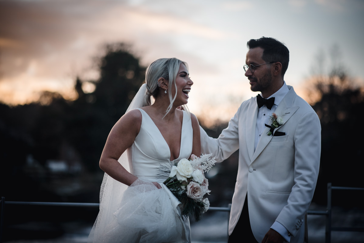 Couple on the banks of the river Derwent at the West Mill Wedding Venue laughing during golden hour portraits